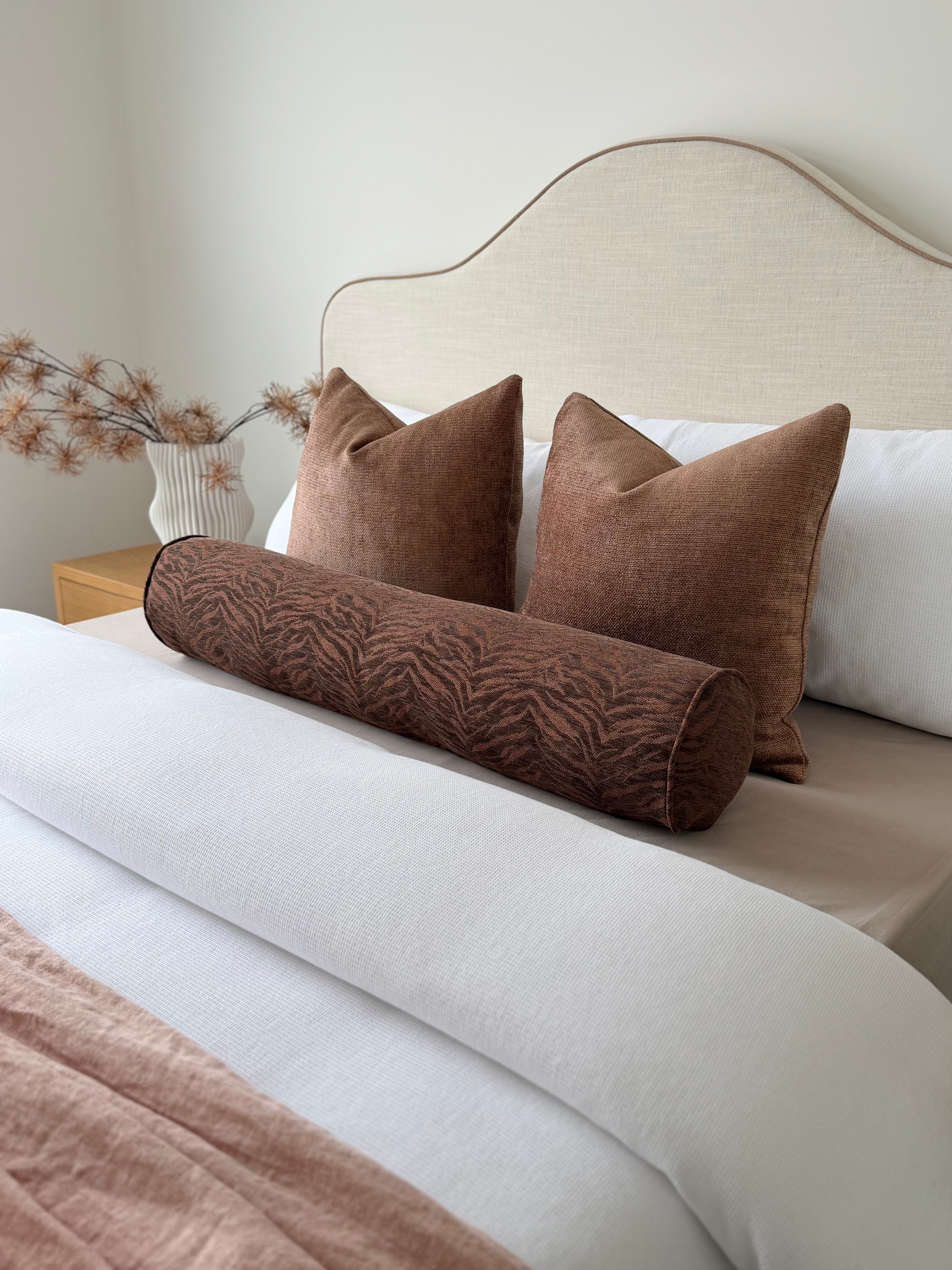 Temba Cocoa chocolate patterned long bolster cushion, 100x18cm, styled across a bed